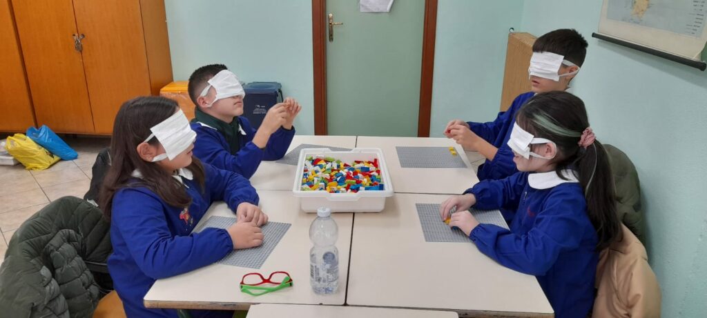 Quattro bambini bendati si approcciano ai LEGO Braille Brick, tramite il tatto.